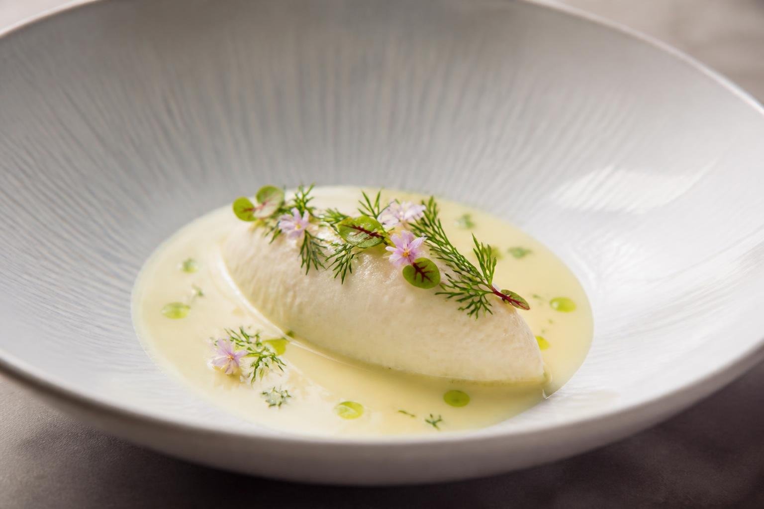 Une quenelle de poisson finement présentée en assiette, garnie d'une sauce délicate
