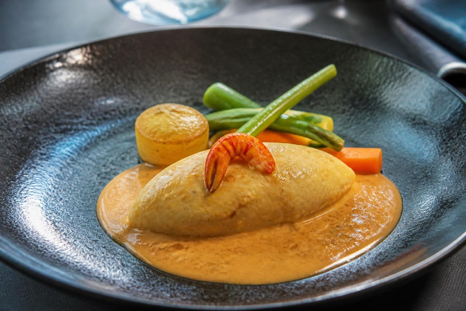 Quenelle de brochet servie avec sauce Nantua et garniture